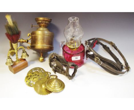 A brass wall mounted oil lamp; a cranberry glass oil lamp; horse brasses; etc