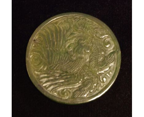 A Chinese spinach jade roundel, carved with a phoenix and a dragon
