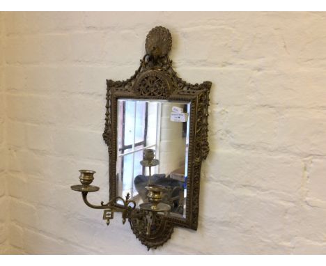 A wall mounted gilt framed mirror with peacock decoration and candlestick holders.