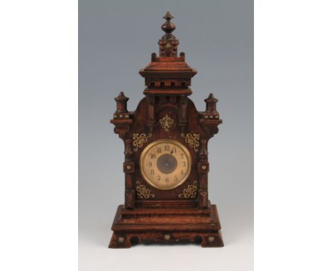 An early 20th Century oak castle shaped mantle clock with carved and turned detailing and finials with applied brass detailin