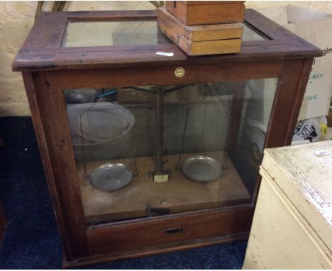 Scientific weighing scales in glazed cased cabinets.