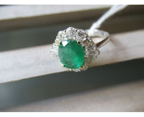 18ct White gold ring set centre oval emerald surrounded by trapezoid and round brilliant cut diamonds 