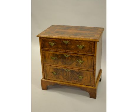 Small reproduction figured walnut and crossbanded three drawer chest raised on bracket feet 