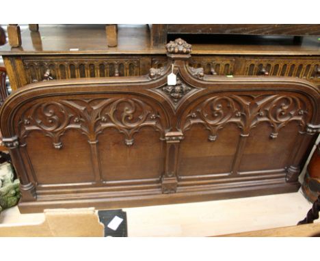 A mid Victorian oak Gothic Revival part bedstead, in the manner of Pugin, with a carved finial, carved and panelled front