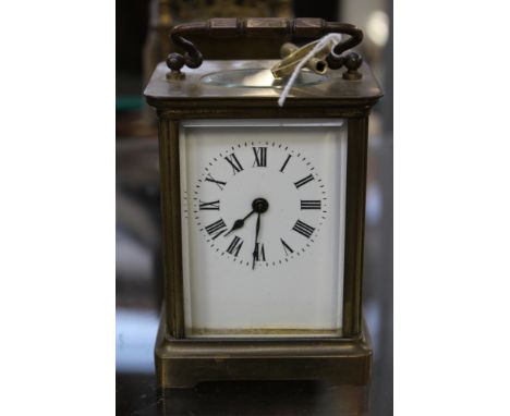 An Edwardian, possibly French carriage clock, brass cased, glass panels enamel dial and Roman numerals with key