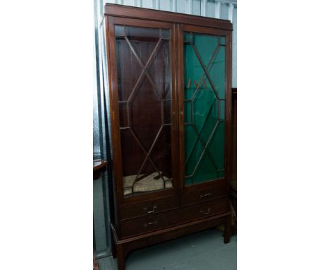 A late Victorian mahogany glazed bookcase and gun cabinet, fitted with two doors, the base section two short and one long dra