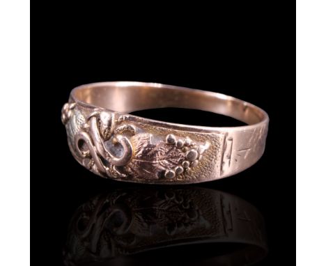 A late 19th / early 20th Century gold ring, the tapering band faced with applied relief adorsed fruiting vines centred by a k