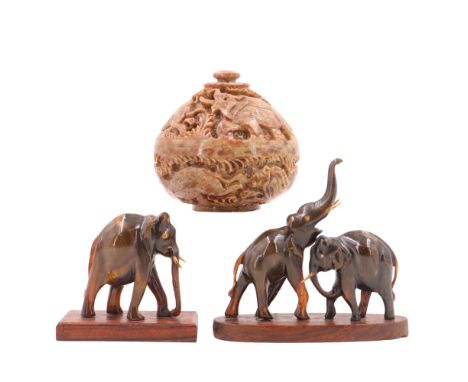 An African carved soapstone lidded pot, decorated in depiction of a lion hunting gazelle, together with two carved elephant f