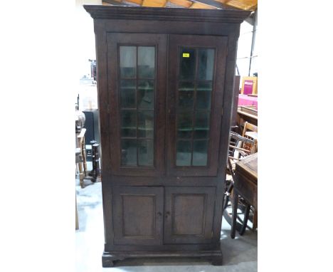 A 19th century joined oak and elm cupboard, enclosed by a pair of glazed doors over a pair of panel doors, on bracket feet. 3