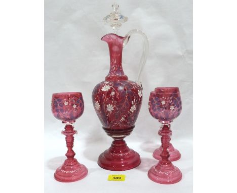 A German ruby glass hock decanter and three goblets with foliate enamel decoration