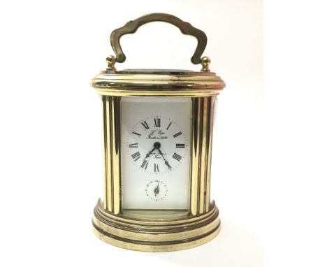 A small French oval carriage clock with Roman numerals, approximate height 8cm, with key.