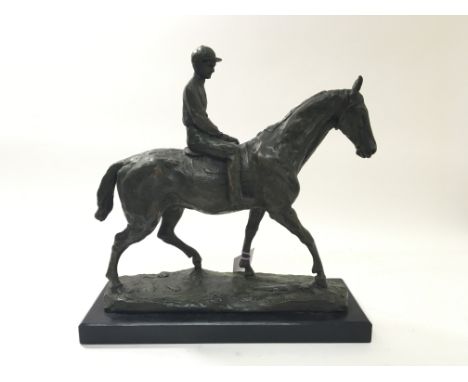 A bronze horse and jockey with textured details on 40cm x 14cm solid black base, the horse being indistinctly signed.