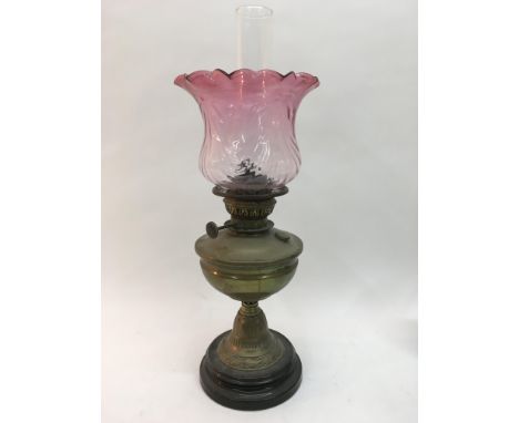 A brass oil lamp with coloured glass shade.