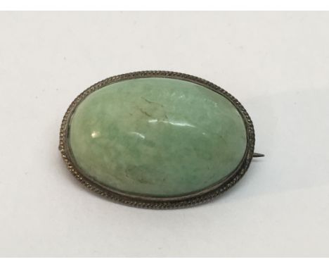 A vintage jade brooch in an oval silver mount.