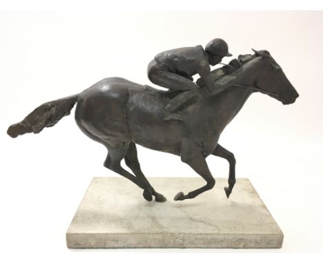 A modern bronze of a jockey riding a horse, on a matt grey marble base.