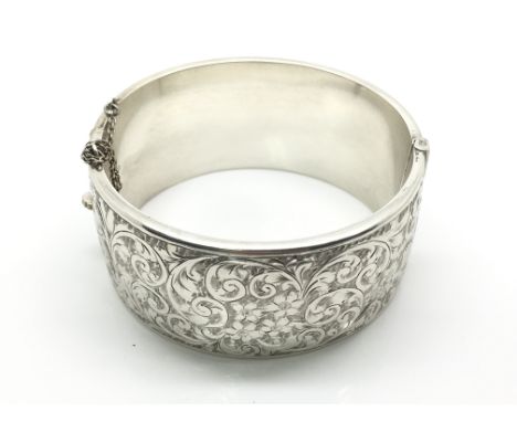 A large silve bangle florally decorated, hallmarked Birmingham 1946, maker S & P, total weight approximately 50 grams, clasp 