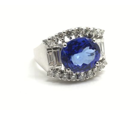 A ladies 14ct white gold ring set with a large central oval cut tanzanite (3.9ct) flanked to the top and bottom by two rows o