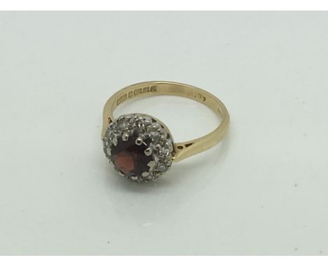 A lady's 18ct gold ring set with a Garnet flanked by diamonds.