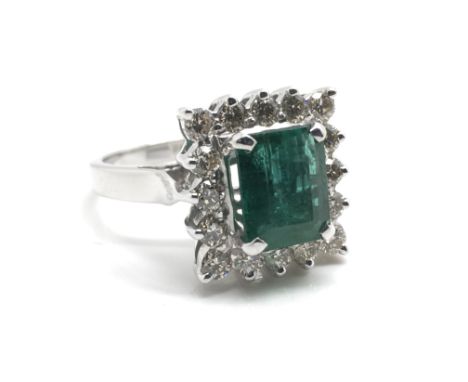 A quality ladies 14ct white gold ring inset with a large central emerald (2.5ct) surrounded by 16 diamonds (0.85ct), ring siz