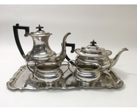 A Garrard & Co silver plated coffee pot, tea pot, cream jug and sugar bowl alongside an unmarked white metal tray, the rear o