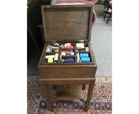 A vintage floor standing wooden sewing box and contents
