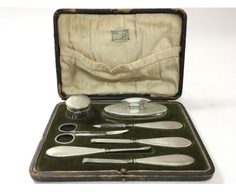 A cased silver engine turned manicure set to include scissors, a file and powder brush, with hallmarks for Birmingham 1945.