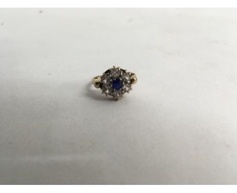 A 9ct gold ring with centre blue stone an white stone surround.