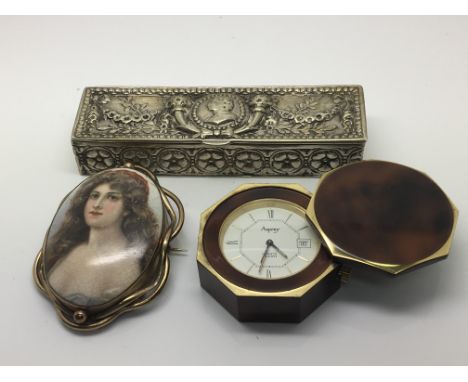An Aspery traveling alarm clock, a continental white metal box of rectangular shape and a porcelain brooch dipicting a portra