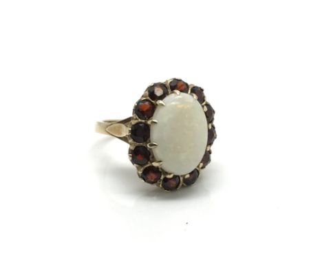 A ladies 9ct gold ring inset with a large central opal surrounded by 12 garnet rubies, ring size approximately N, total weigh