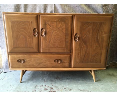 An Ercol sideboard, the right hand side having one large cupboard the inside with a drawer and a,all shelf, the left hand sid