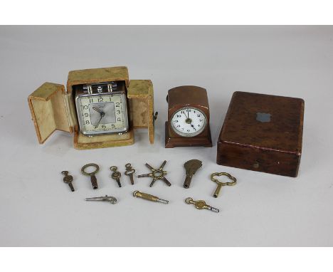A collection of clock and watch keys, one watch key modelled as a pistol, two travelling alarm clocks, and a fruitwood pocket