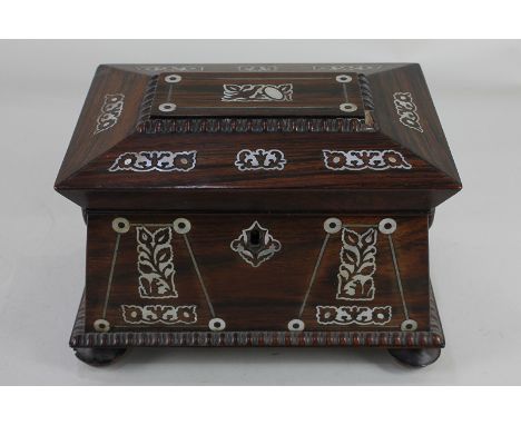 A 19th century rosewood tea caddy inlaid with mother of pearl, of sarcophagus form, with ring handles on bun feet 21.5cm wide