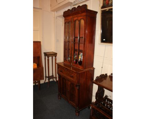 A Victorian flame mahogany secretaire bookcase, with carved frieze above two panel glazed doors enclosing two shelves, the lo