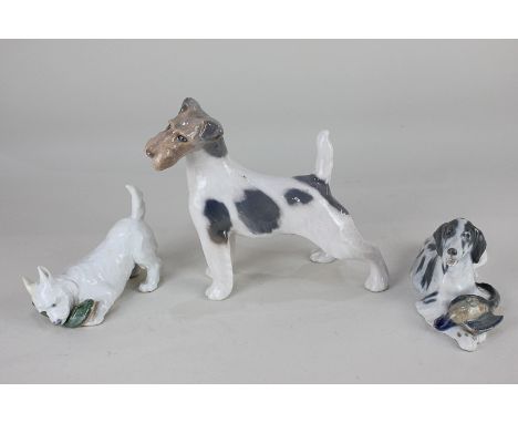 Three Royal Copenhagen porcelain models of dogs, including a fox terrier, a hound with a game bird, and a terrier with a shoe