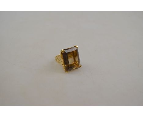 A large step cut smoky quartz set ring in yellow metal four claw setting with rope style bezel and shank, stone measures 25mm