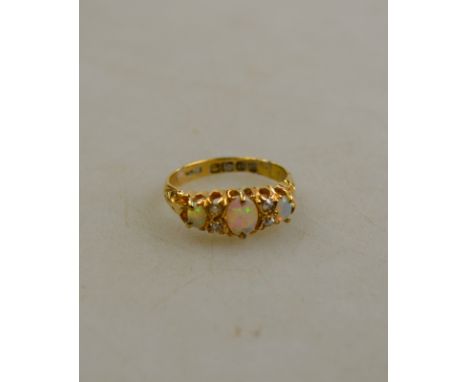 An opal and diamond seven stone ring, 18ct yellow gold claw setting with carved shoulders, size J 1/2