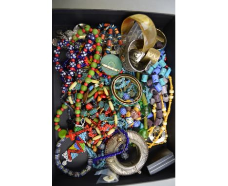 A large quantity of coloured ethnic bead necklaces to/w metal anklet, eight metal bangles and including lucite, and a horn ba