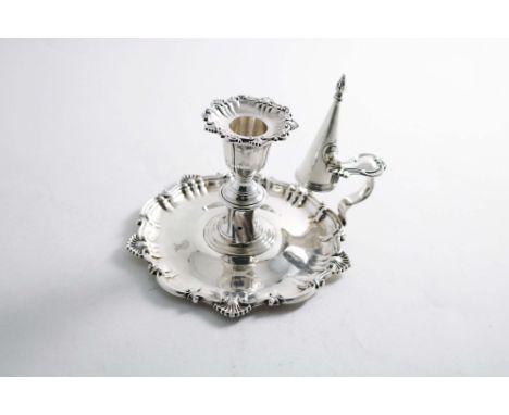 A VICTORIAN CHAMBERSTICK of shaped circular outline, with a shell and scroll border, engraved with a crest, complete with noz