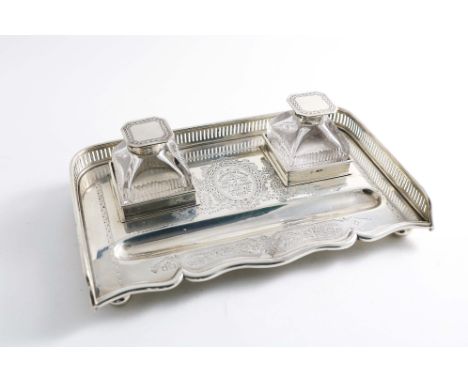 A LATE VICTORIAN INKSTAND with a pierced gallery and engraved decoration, fitted with two mounted cut-glass bottles, the cart