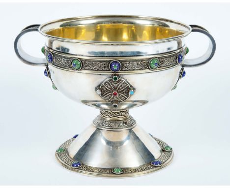 AN EARLY 20TH CENTURY IRISH REPRODUCTION OF THE ARDAGH CHALICE parcelgilt with applied strapwork, set with coloured enamel an