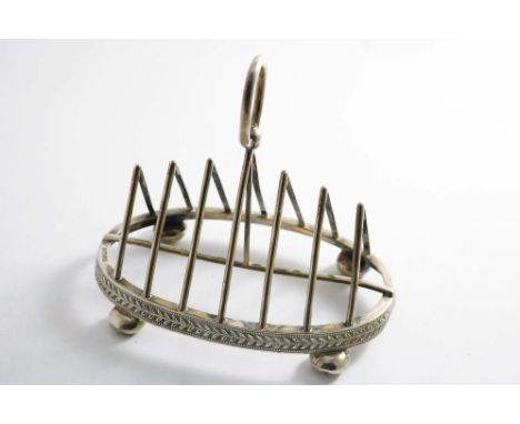 A VICTORIAN TOAST RACK with seven triangular bars, button feet and an oval base, decorated with a repeating foliate frieze, b