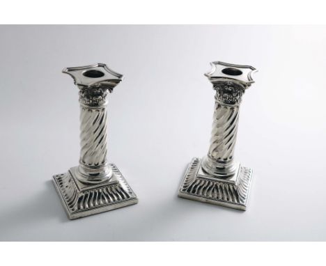 A PAIR OF LATE VICTORIAN DWARF CANDLESTICKS with wrythen-fluted columns, Corinthian capitals with detachable nozzles and beve