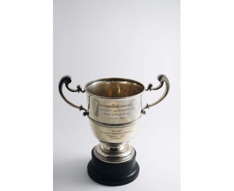 AN EARLY 20TH CENTURY TROPHY CUP with twin, harp-shaped scroll handles, a campana-shaped bowl and an applied girdle, inscribe