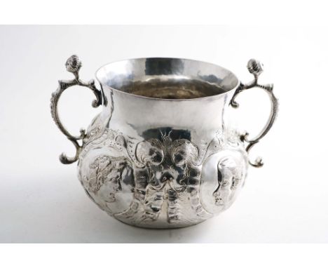 A LATE COMMONWEALTH / EARLY CHARLES II LARGE PORRINGER of bellied form with a flat base, cast mask &amp; scroll handles and a