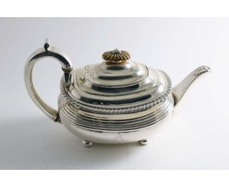 A GEORGE III TEA POT on button feet with a reeded band around the body, a gadrooned rim and an ivory finial, crested, maker's