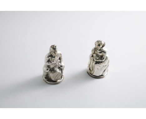 A PAIR OF EARLY 20TH CENTURY DANISH NOVELTY PEPPERETTES in the form of an old gentleman sitting astride a barrel with his pip