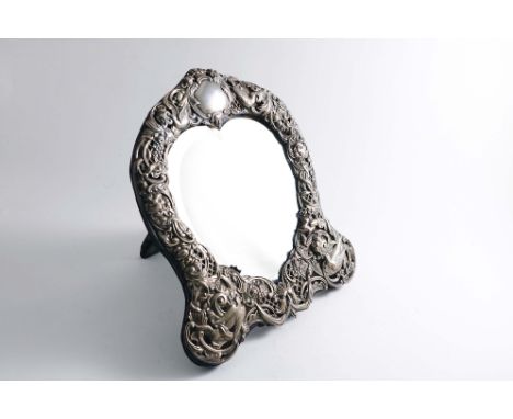A LATE VICTORIAN MOUNTED HEART-SHAPED MIRROR FRAME with pierced and embossed decoration around the border and an easel back, 