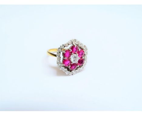 An 18ct gold ruby and diamond ring, the central diamond 0.25ct approx framed by six rubies all in a diamond set halo, 1.8cm d