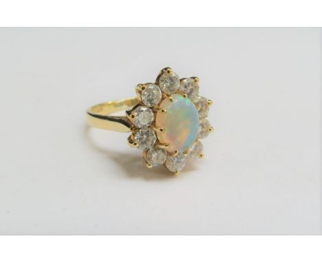 An 18ct gold opal and diamond cluster, the central opal framed by ten 0.10ct approx diamonds. Size L/M, 4.4g 