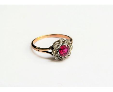 A gold ring set with a circular ruby in a halo of old cut diamonds, marks rubbed. Size N, 1.9g 